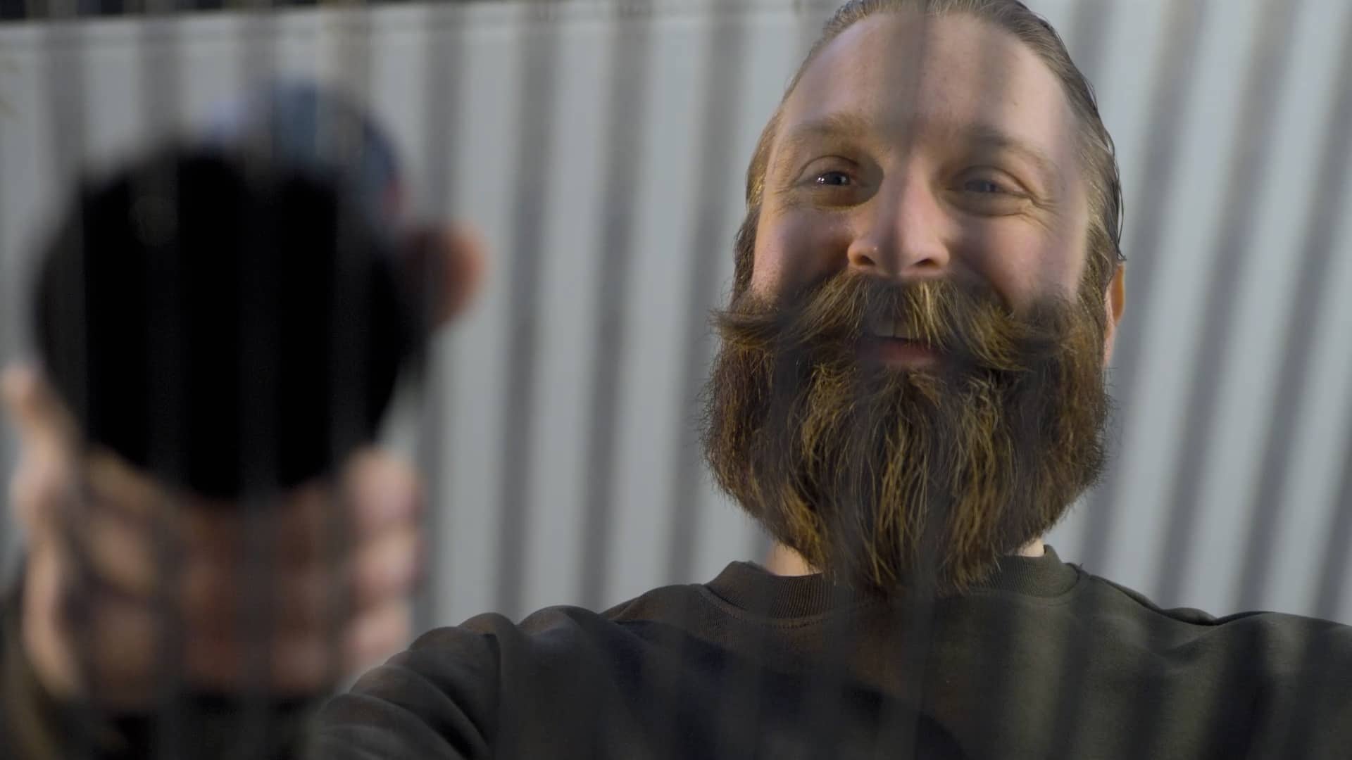 Darsteller schaut lächelnd beim Benutzen des Bosch Universal Brush durch ein Gitter.