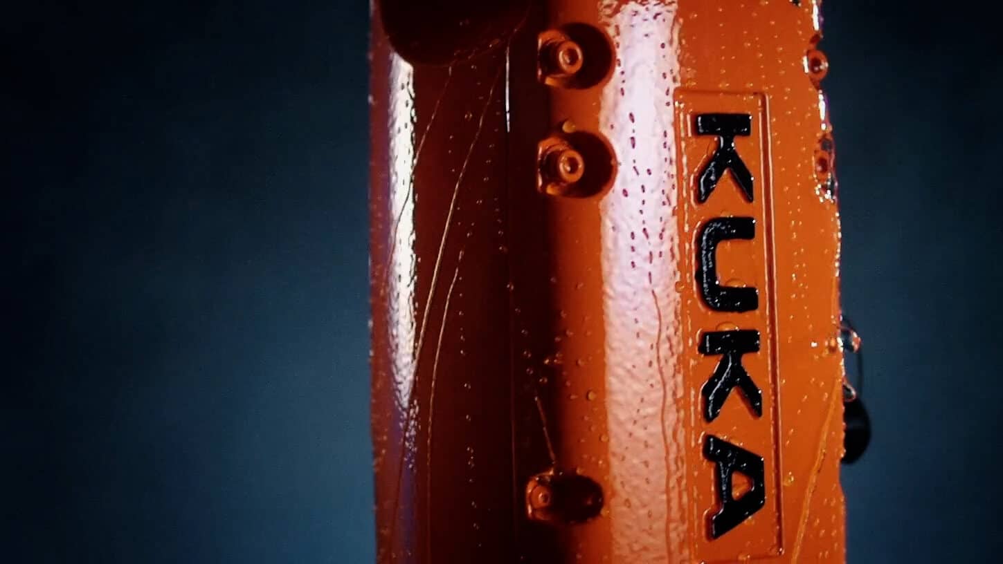 Ein eindrucksvoller orangefarbener KUKA Agilus Roboterarm mit aufgedrucktem Firmennamen in schwarz.