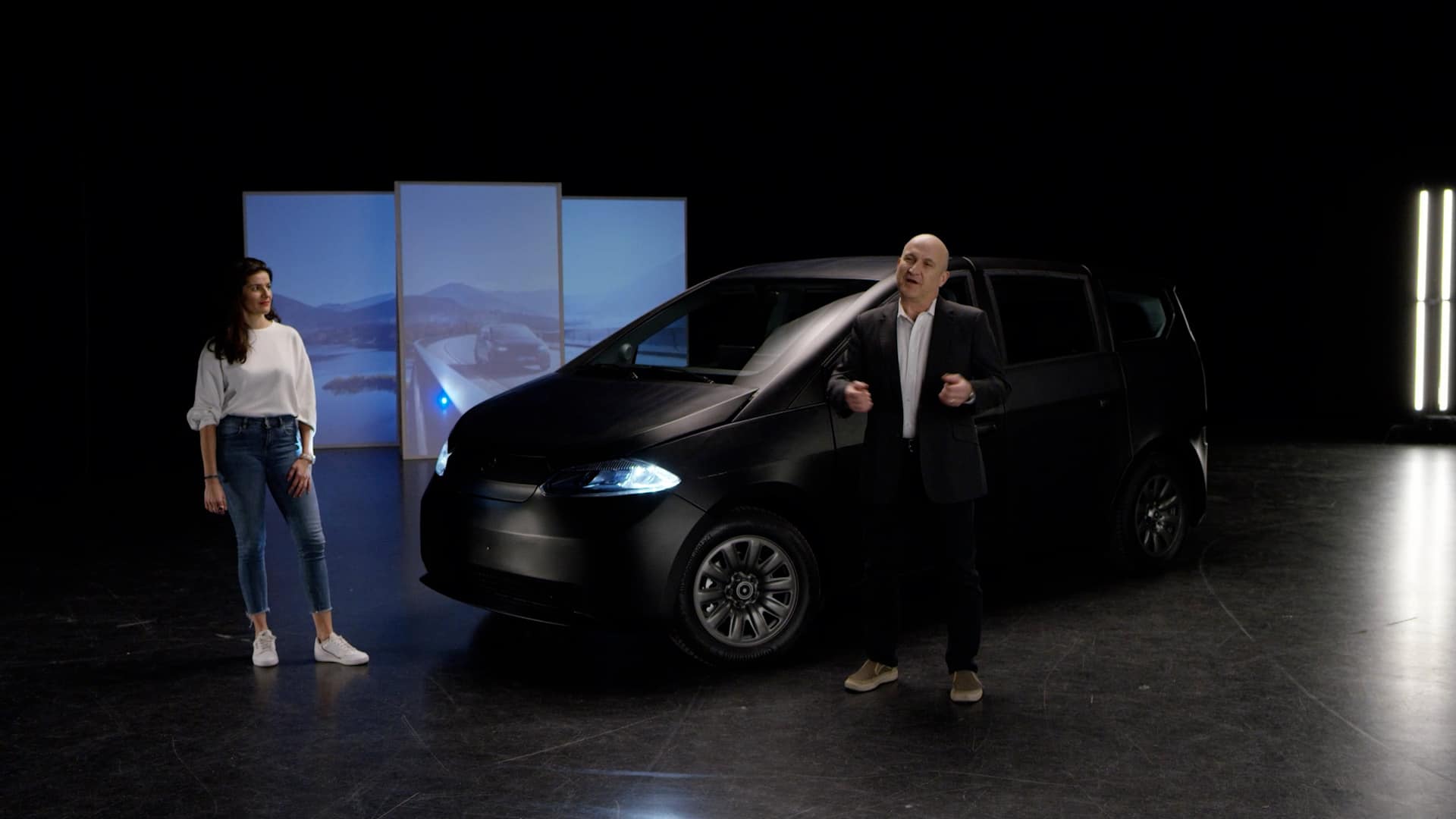 Zwei Sono Motors Mitarbeiter präsentieren das schwarze Sion Fahrzeugmodell.