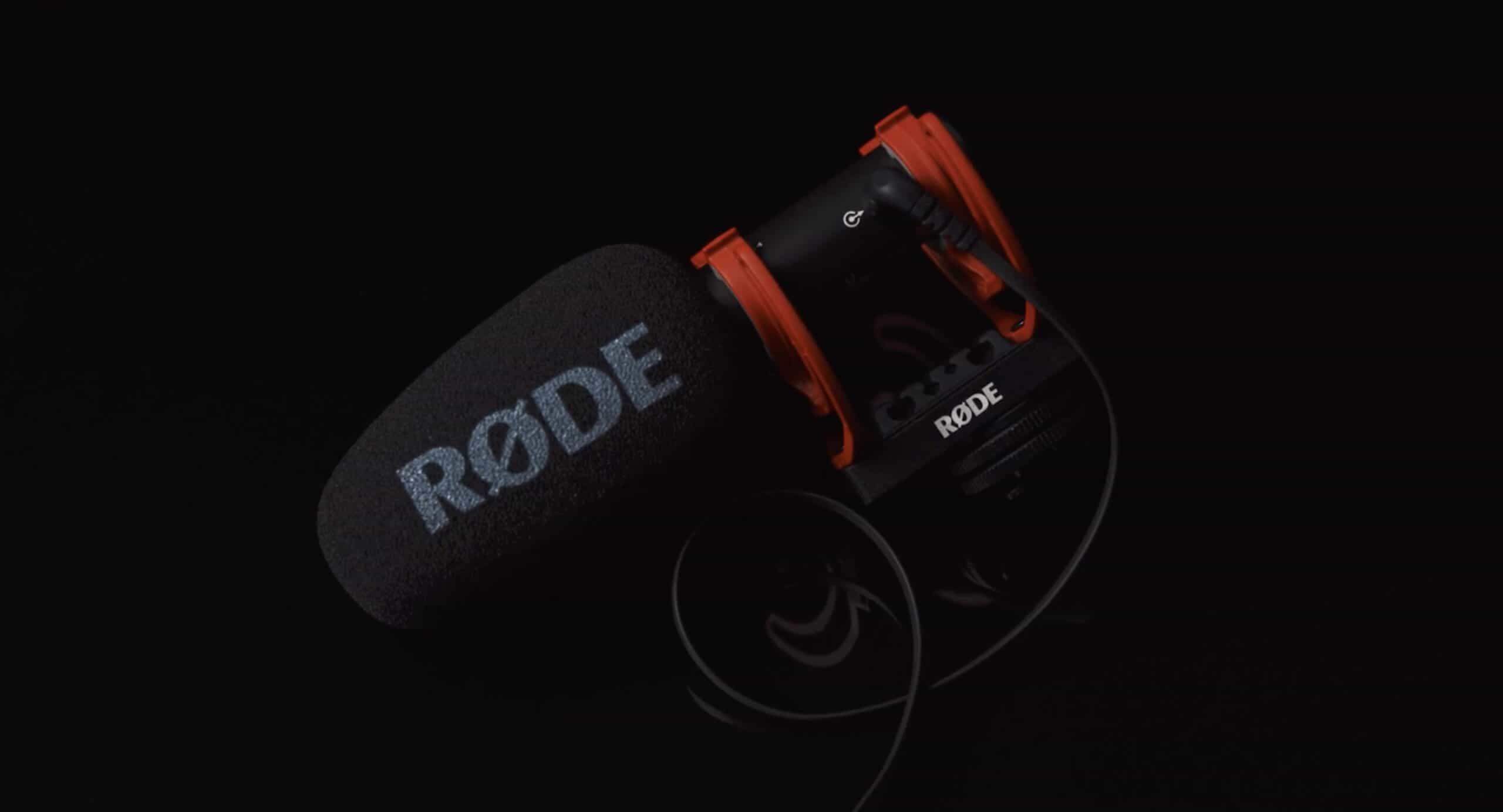 Seitliche Aufnahme des schwarzen Kamera Mikrofons von Rode mit roter Halterung und Fokus auf der Marke.